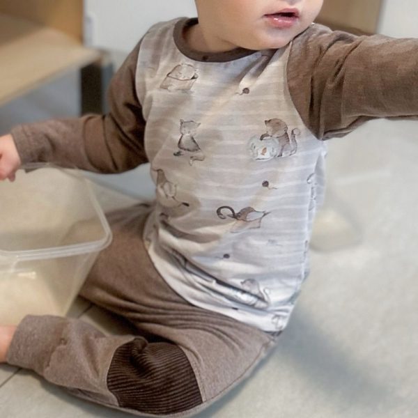 Basic Langarmshirt für Babys & Kinder - liebevoll handgemacht aus weichem Jersey mit Katzen-Motiv und Uni-Farbenen Ärmeln in hellem Braun; das Baby auf dem Foto trägt dazu eine Räuberhose mit robustem Cord im Kniebereich